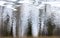 Blurred reflection of blue sky, sihouette of people and trees standing near spring puddle.