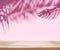 Blurred shadow of tropical palm leaves on the pink wall and table top in the foreground. Summer concept