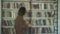 Blurred shot of male student on the background of bookshelves in the library