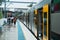 Blurred shot of suburban train station with passengers and train with open doors on a rainy day