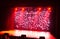 Blurred show red background. Bright red light beams spotlights on stage at time of entertainment show. Laser and lights show.