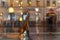 Blurred silhouette of an abstract unrecognizable girl with bags, view through a wet window with raindrops, city street in dark