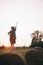 Blurred silhouette of happy woman on haystack   and focus on going train in sunset summer field