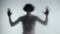 A blurred silhouette of a man with a bare torso behind a frosted curtain or glass. The man touches the glass with his