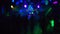 Blurred silhouettes of dancing people in a nightclub under the colored light of spotlights