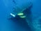 Blurred silhouettes of divers near a sunken ship at the bottom of the Indian Ocean