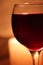 Blurred soft focus bokeh of glass full of red wine glowing from candle light winery background