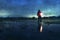 A blurred spooky figure, holding a lamp. Reflected in a flooded field in the countryside. On an atmospheric winters evening. With