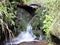 Blurred stream of a mountain stream flowing under a small stone crevice