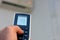 blurred view of a human hand with its thumb pressing an air conditioner remote control to turn on the air conditioning fan