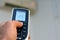 blurred view of a human hand with its thumb pressing an air conditioner remote control to turn on the air conditioning fan