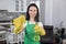 Blurred view of pretty smiling young female cleaner in gloves and apron, spraying cleaner detergent to camera and making