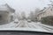 Blurred view of snow covered street through wet windshield of car on snowy, rainy spring day