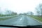 Blurred view of suburban road through wet car window.