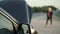 Blurred view of a woman stopping by hitchhiking near a broken car