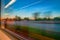 Blurred window view from a train in motion. Train is traveling by rail, nature outside, blurred lights. Sunset sky and city.