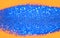 Blurry background of blue glitter sparkles on orange surface