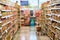 Blurry background texture of aisle between shelves filled with goods in supermarket environment