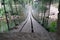 Blurry background of A wooden bridge fasteners with wire rope sling used crosses the stream