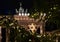 Blurry fir branches of Christmas tree with shiny lights on foreground and focus to Brandenburg Gate illuminated Jewish David star