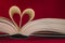 Blurry heart made from book pages over red background