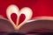 Blurry heart made from book pages over red background