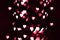 Blurry lights on a dark background. Festive bokeh background in the form of hearts for Valentine's Day. Soft focus