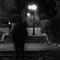 Blurry male figure walking in park with lampposts at night