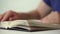 Blurry person in blue dressing flips book pages closeup