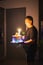 Blurry photo of  a dad father holds a cake with burning candles for a childâ€™s birthday surprise at home