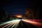 a blurry photo of a highway at night with a long exposure of the light from the car\\\'s headlights on the side of the road