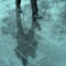 Blurry reflection legs and shadow, silhouette of a man in the wet sidewalk, in a puddle walking on a rain