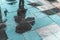 Blurry reflection shadow silhouette of a girl walking under umbrella in a pedestrian city wet street in a puddle, autumn