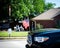 Blurry senior couple waving hands with modern pickup truck driving on residential street smalltown Fourth of July parade, Dallas,