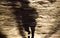 Blurry shadow silhouette of a person running on city street side