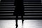 Blurry silhouette of young elegant woman climbing up the city st