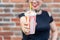 Blurry young positive girl holds in Ruach a milkshake with a straw against a brick wall background. Summer dessert and
