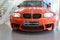 BMW 1M: Front panoramic view, coupe, orange, with the headlights on