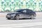 BMW 3 Series car rushes on the road with blurred background. Black dusty BMW 330d sedan G20 car moving on the street