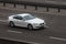 BMW coupe white rides on the road. Against a background of blurred trees