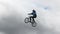 BMX bicycle man jumps high cloudy background slow motion