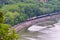 BNSF train engine pulling a string of tank cars along the Mississippi river