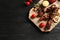 Board with barbecued meat, garnish and sauces on wooden background, top view