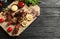 Board with barbecued meat, garnish and sauces on wooden background, top view.