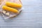 Board with boiled corncobs on wooden table