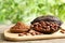 Board with cocoa pods, beans and powder on table against blurred background