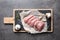 Board with cut raw turkey fillet and ingredients on grey background