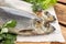 Board with delicious salted herrings and herbs on wooden table, closeup