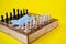 Board game, wooden chess and a medical mask on a yellow background