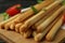 Board with grissini breadsticks on wooden table, close up